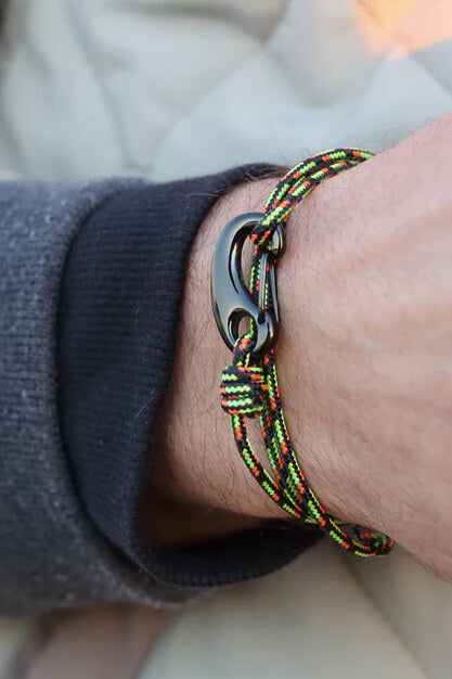 Close-up of a wrist wearing a colorful braided bracelet with a metal clasp.