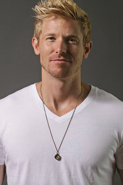 Man wearing a white t-shirt and necklace against a gray background