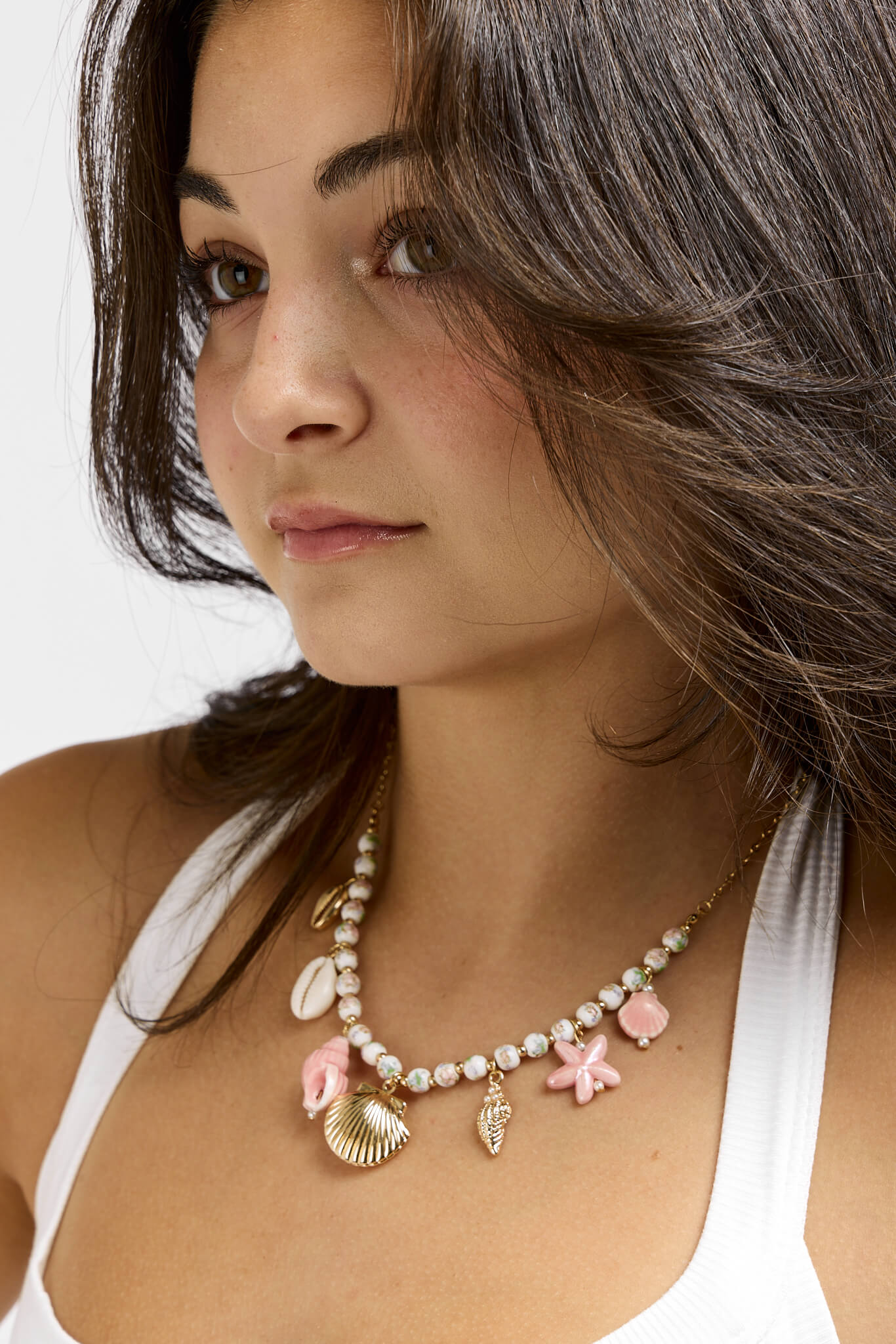 Womens gold necklace with white beads and pink and gold charms throughout