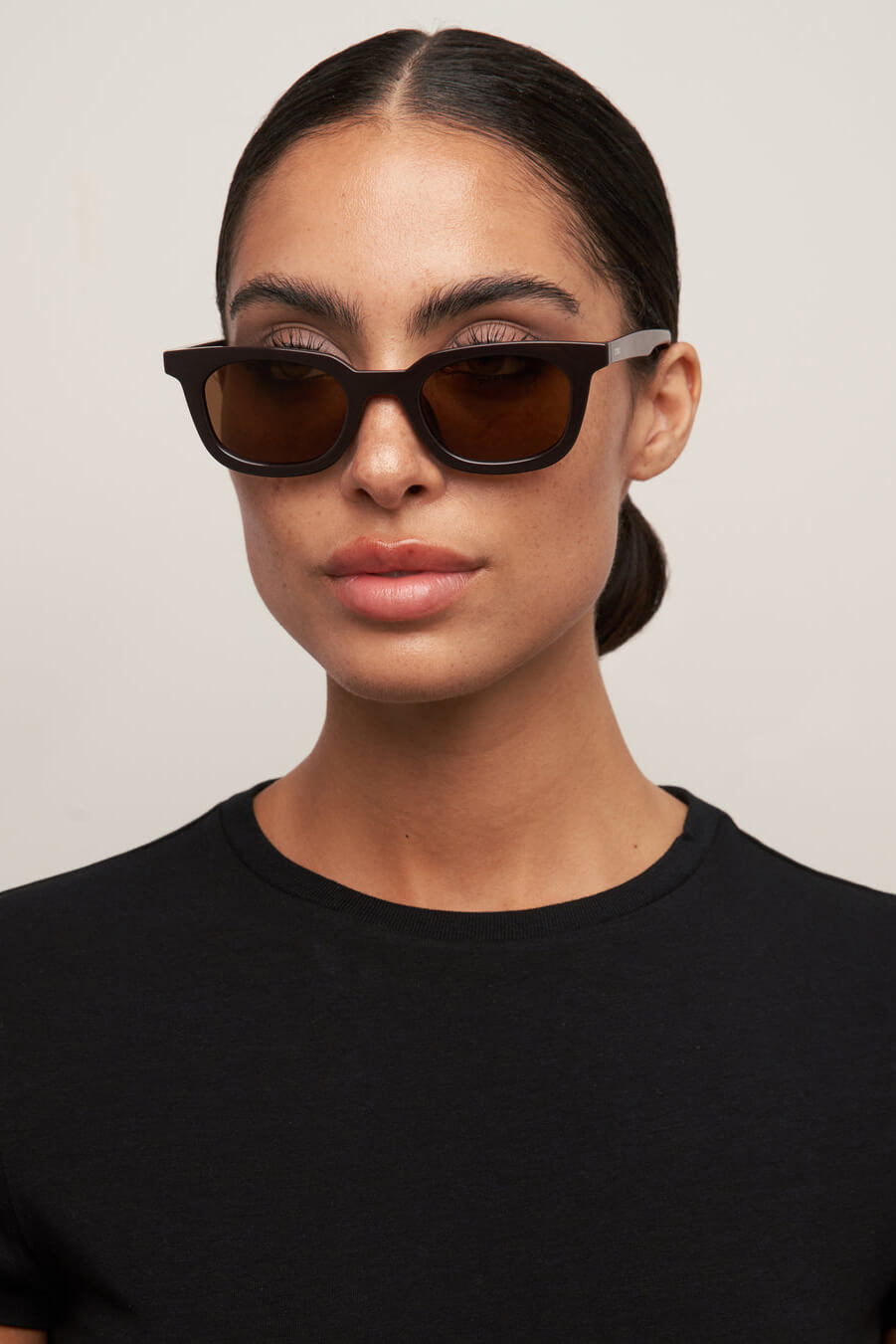 Woman wearing dark sunglasses against a plain background