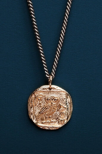 Gold coin pendant necklace on a blue background