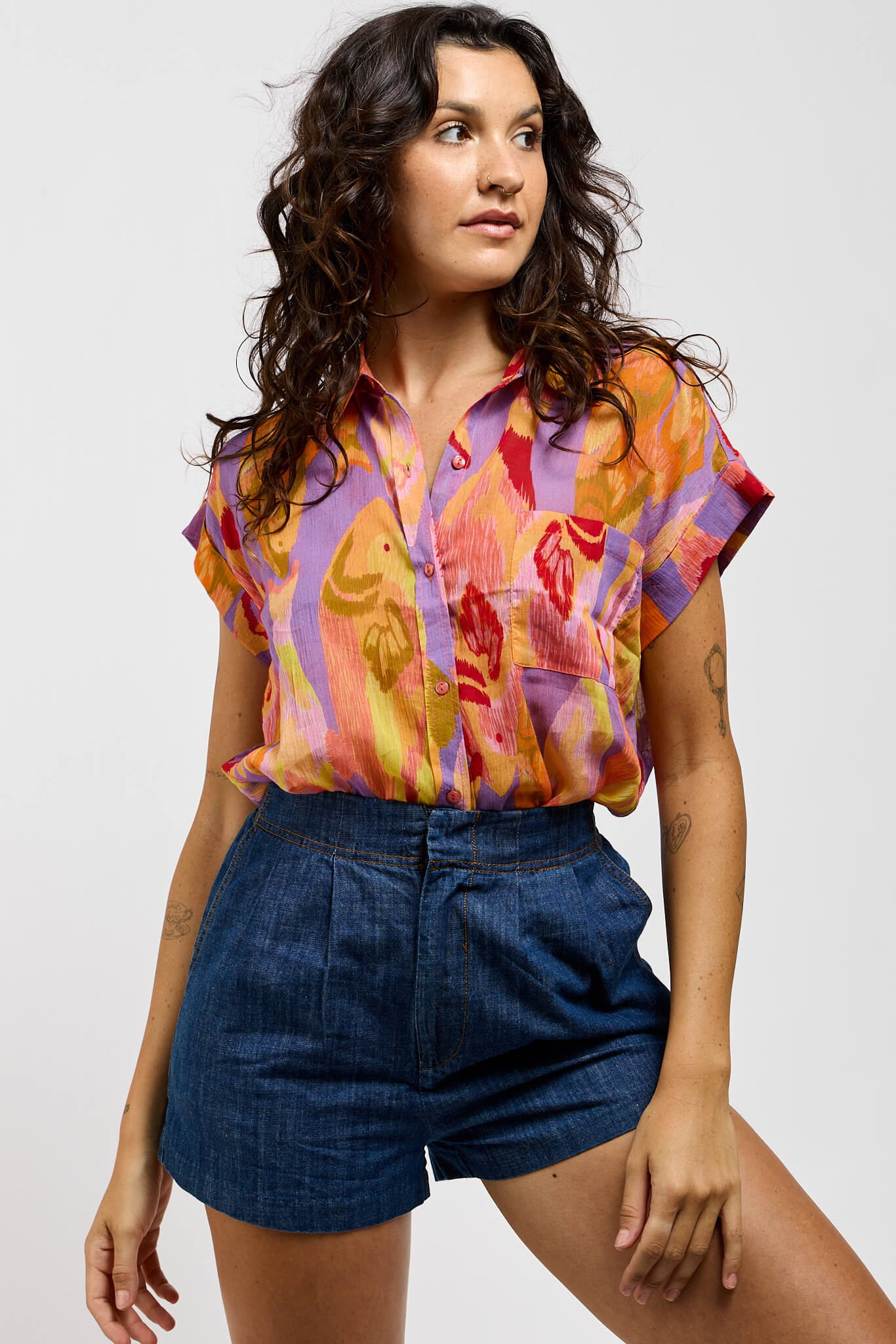 Womens buttonup shirt that has a print of oranges, purples, and red